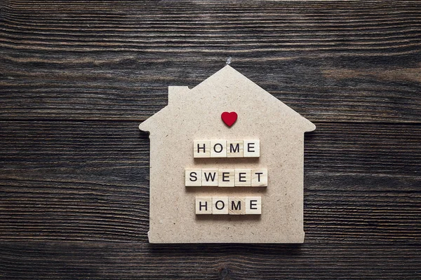 Teklif ve kalp şeklinde ahşap arka plan üzerinde ev sembolü.