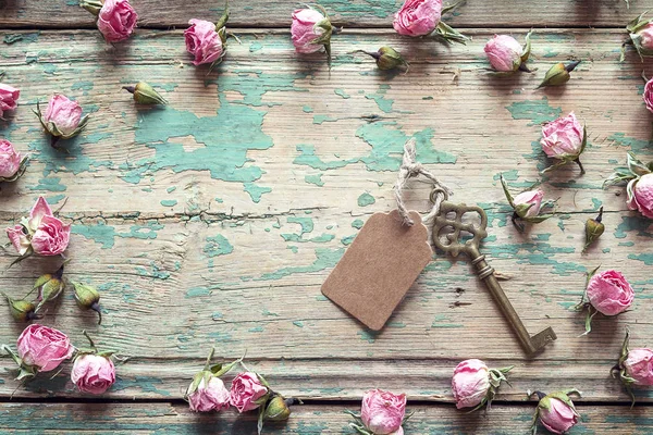 Llave vintage con una etiqueta y un poco de rosas rosadas en una madera vieja — Foto de Stock