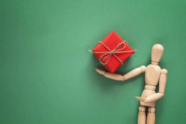 Klasik ahşap kukla Noel hediyesi yeşil arka plan üzerinde tutar..