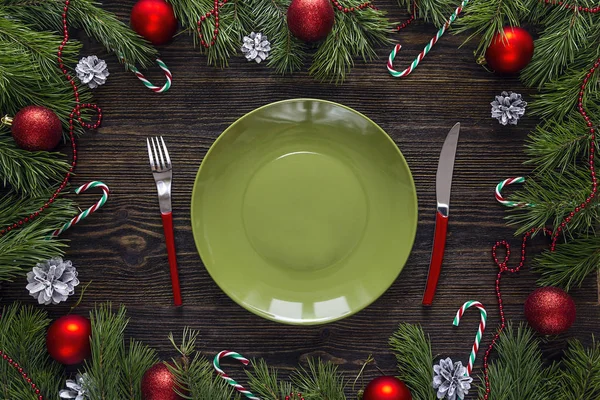 Empty green plate with knife and fork and Christmas decorations — Stock Photo, Image