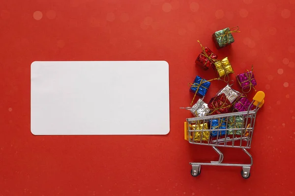 Carro de la compra con cajas de regalo y etiqueta en blanco para texto en rojo — Foto de Stock