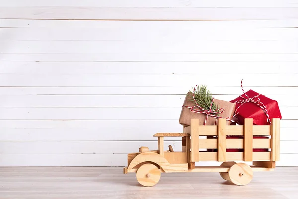 Caixas de presente de Natal em caminhão de brinquedo de madeira em backgro de madeira branca — Fotografia de Stock