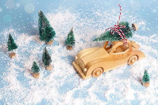 Carro de brinquedo de madeira com árvore de Natal no telhado na neve azul de volta — Fotografia de Stock