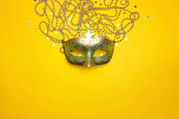 Festliche Karnevalsmaske und Perlen auf gelbem Hintergrund. — Stockfoto