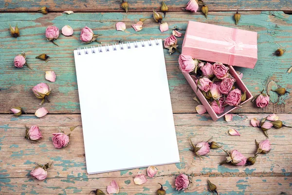 Clean open notebook and gift box with pink dried rose flowers on — Stock Photo, Image