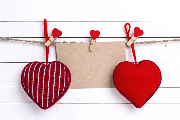 Tarjeta de papel en blanco con corazones rojos colgando en pinzas de ropa en blanco —  Fotos de Stock