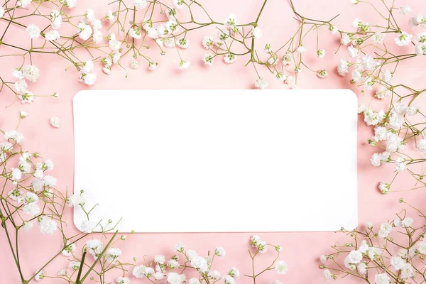 Carta di carta bianca con delicati fiorellini bianchi sul retro rosa — Foto Stock