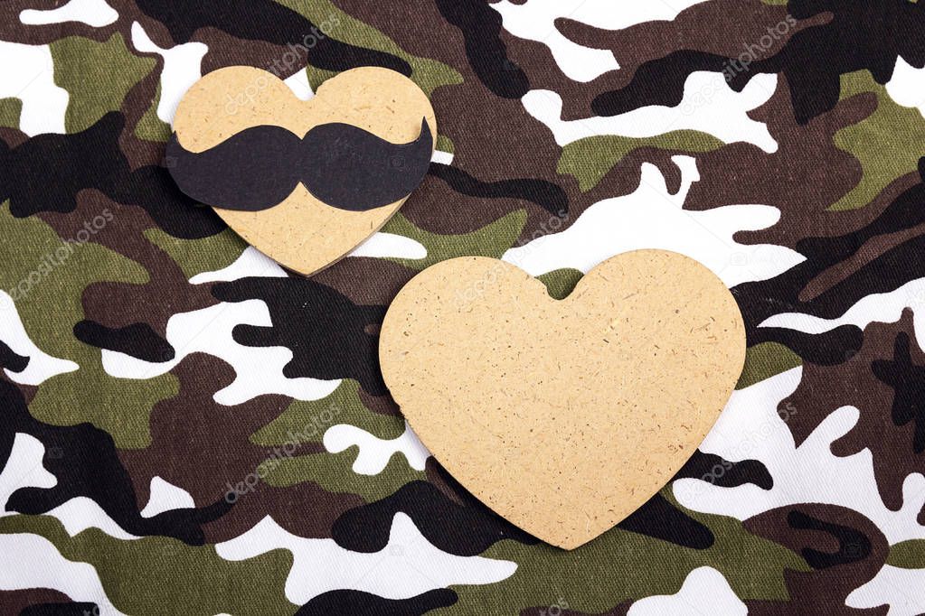 Wooden hears on military camouflage background. Place for text. 