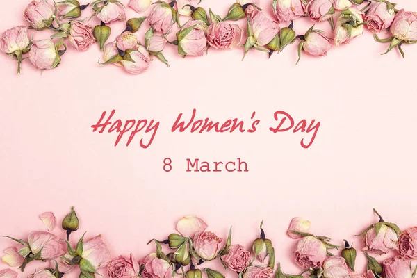 Mensaje de saludo del Día de la Mujer con pequeñas rosas secas sobre fondo rosado —  Fotos de Stock