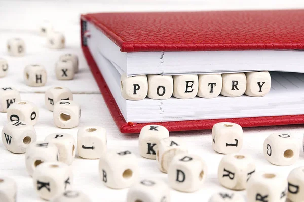 Word Poetry written in wooden blocks in red notebook on white wo Royalty Free Stock Images