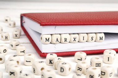 Word Marxism written in wooden blocks in red notebook on white w clipart