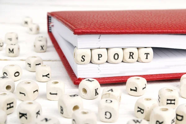 Word Sport geschreven in houten blokken in laptop op witte houten — Stockfoto