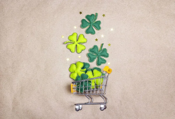 Nákupní vozík s čtyři - leaf clover na hnědém papírovém pozadí — Stock fotografie