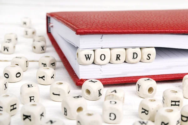 Ord ord skrivna i träklossar i röda anteckningsboken på vitt woo — Stockfoto