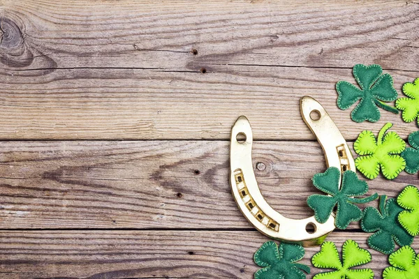 Golden horseshoe and clover leaves on old wooden boards. Space f — Stock Photo, Image