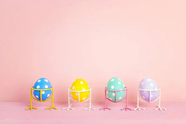 Funny Easter eggs on bird legs on pink background. Space for tex