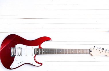 Beyaz ahşap masa üzerinde kırmızı elektro gitar. 