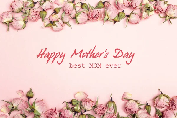 Mothers Day greeting message with small dry roses on pink backgr