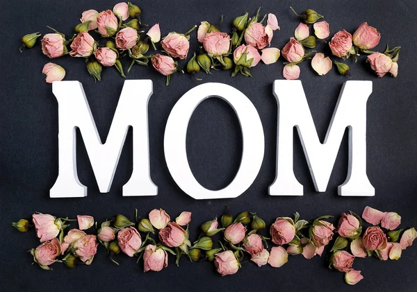 Word MOM with small pink roses on black background. — Stock Photo, Image