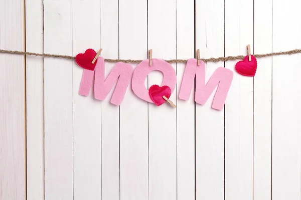 Letras cor-de-rosa MOM pendurar em clothespins em fundo de madeira branca . — Fotografia de Stock