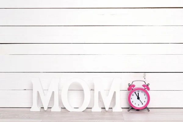 Cartas MOM con despertador rosa sobre fondo de madera blanco . — Foto de Stock