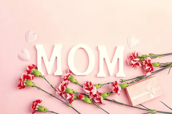 Mother's Day background with carnation flowers and gift box on p — Stock Photo, Image