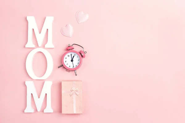 Mother\'s Day background with alarm clock and gift box on pink. C