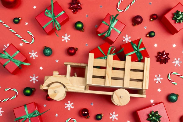 Dřevěný autíčko s červenými dárkovými krabicemi obklopený vánoční gif — Stock fotografie