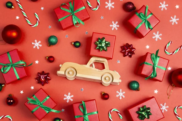 Drewniany samochodzik z pudełkiem prezentów na dachu otoczony Bożym Narodzeniem — Zdjęcie stockowe