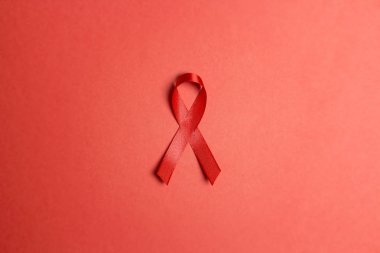 Kırmızı arkaplanda AIDS farkındalığının sembolü olarak kırmızı kurdele. 