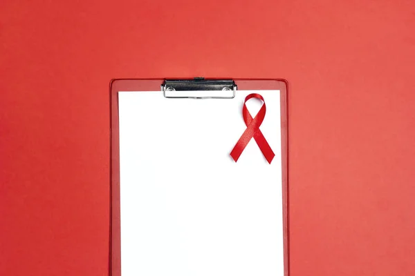 Empty medical folder with red ribbon as symbol of aids awareness