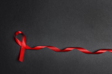 Siyah arkaplanda AIDS farkındalığının sembolü olarak kırmızı kurdele 