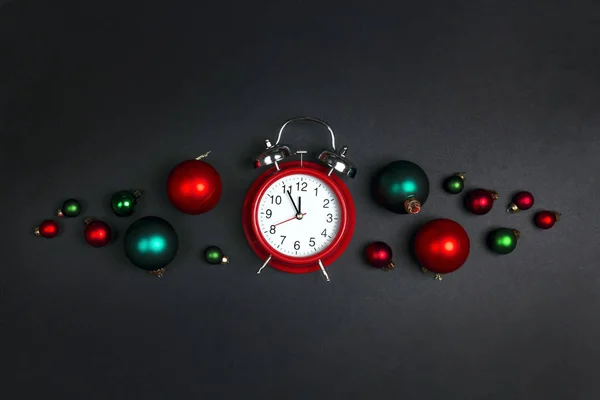 Wekker klok met kerstballen op zwarte achtergrond. — Stockfoto