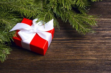 Noel kırmızı hediye kutusu ve ahşap arka planda köknar dalları. 