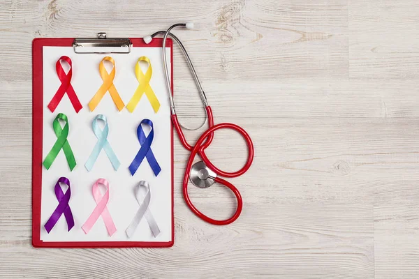 Medical folder with a stethoscope and colorful awareness ribbons — 스톡 사진