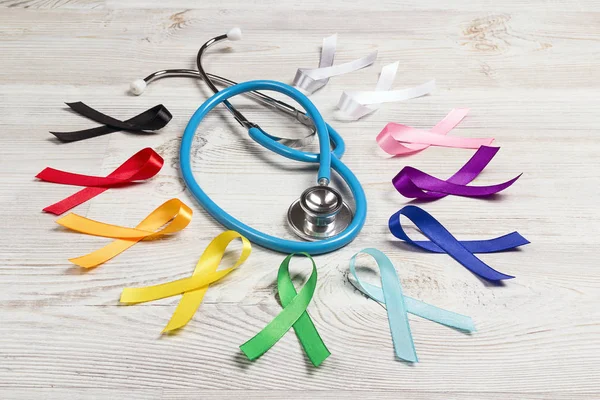 Colorful awareness ribbons with a stethoscope on wooden table. W — 스톡 사진