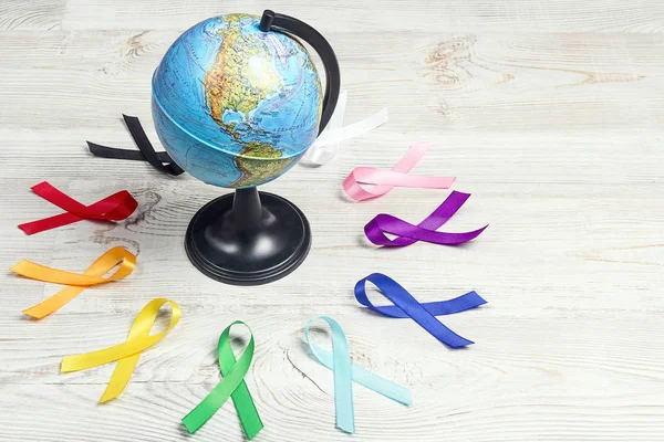 De globe met cirkel van kleurrijke bewustzijnslinten op houten ta — Stockfoto