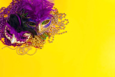 Sarı arka planda festival maskeleri ve boncukları..