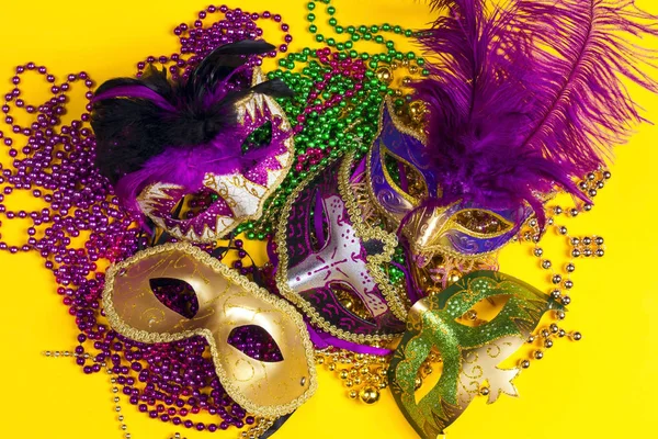 Slavnostní karnevalové masky a korálky na žlutém pozadí. — Stock fotografie