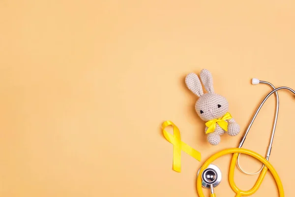 Consapevolezza del cancro infantile nastro giallo con coniglietto giocattolo e stet — Foto Stock