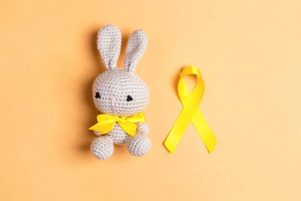 Childhood Cancer Awareness Golden Ribbon with toy bunny on yello — 스톡 사진