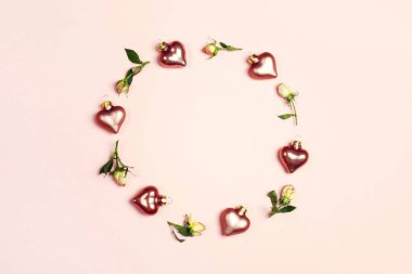 Gül çiçeklerinden yapılmış yuvarlak çerçeve ve pembe kalpler.