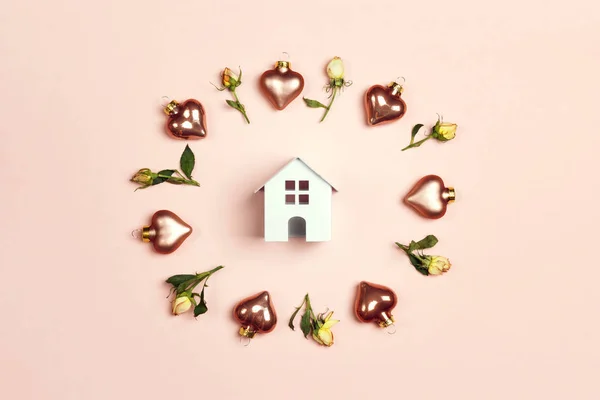 Μινιατούρα λευκό παιχνίδι σπίτι που περιβάλλεται από καρδιές και τριαντάφυλλα σε ροζ — Φωτογραφία Αρχείου