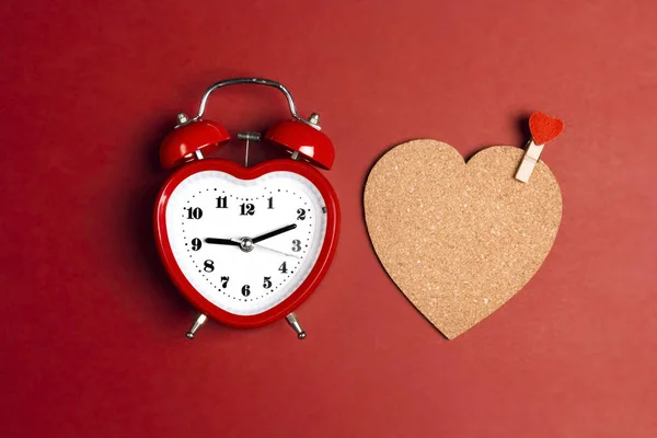 Ρομαντικό ξυπνητήρι και καρδιά από φελλό με μανταλάκι σε κόκκινο φόντο — Φωτογραφία Αρχείου