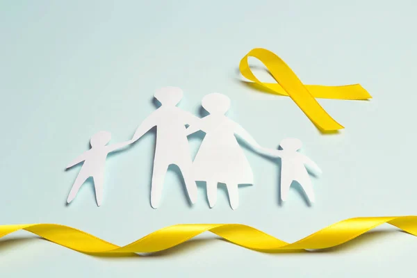 Paper family silhouette with yellow awareness ribbon on a blue b