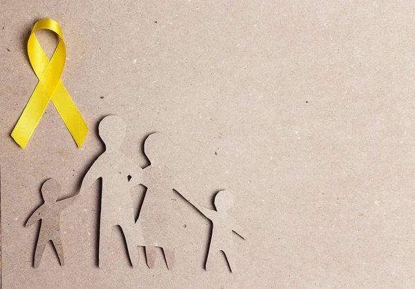 Kartonnen familiesilhouet met geel bewustzijnslint op kaart — Stockfoto
