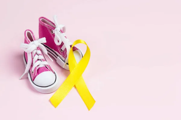 Babyskor med barncancer medvetenhet gyllene band på rosa — Stockfoto