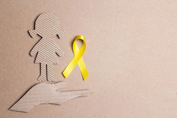 Barncancer medvetenhet Golden Ribbon med flicka kartong dol — Stockfoto