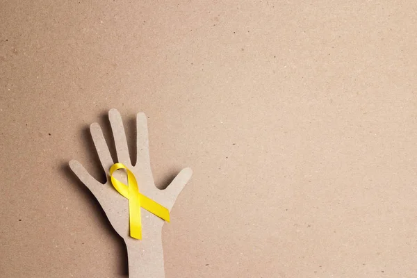 Cardboard hand silhouette with yellow awareness ribbon and copy — 스톡 사진