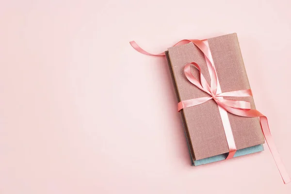 Libros de regalo vendados con una cinta rosa sobre un fondo rosa . — Foto de Stock